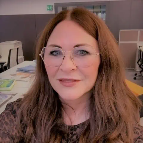 A woman in glasses is capturing a selfie during storytelling training in an office.
