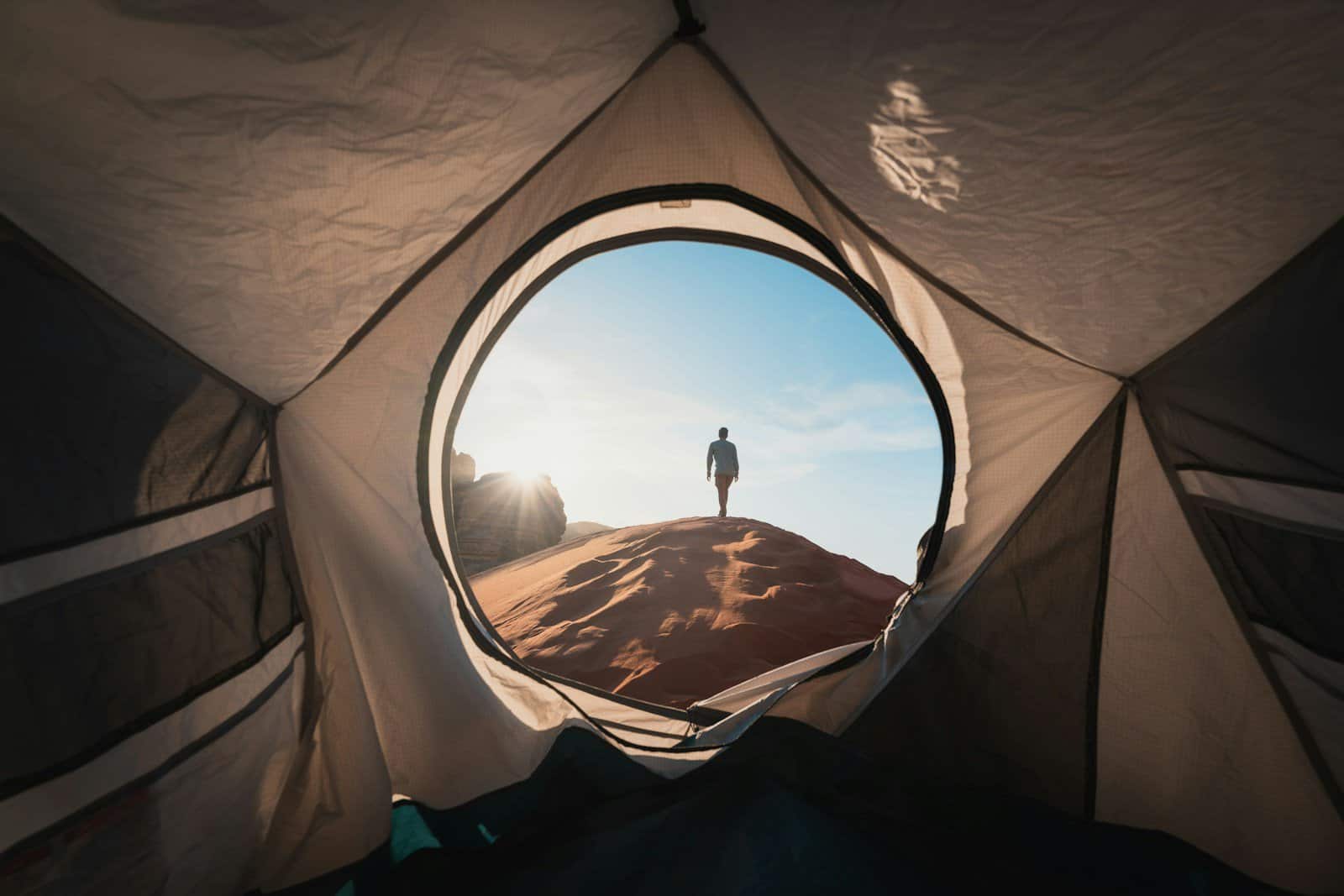 a man standing in a tent looking out into the distance