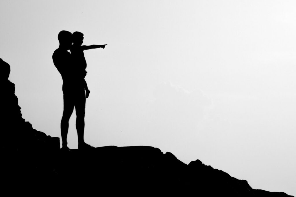 silhouette of man carrying child