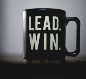a black coffee mug with the words lead win printed on it