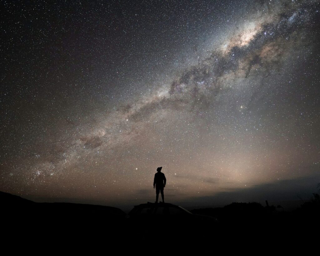 2 a man standing on top of a hill under a night sky
