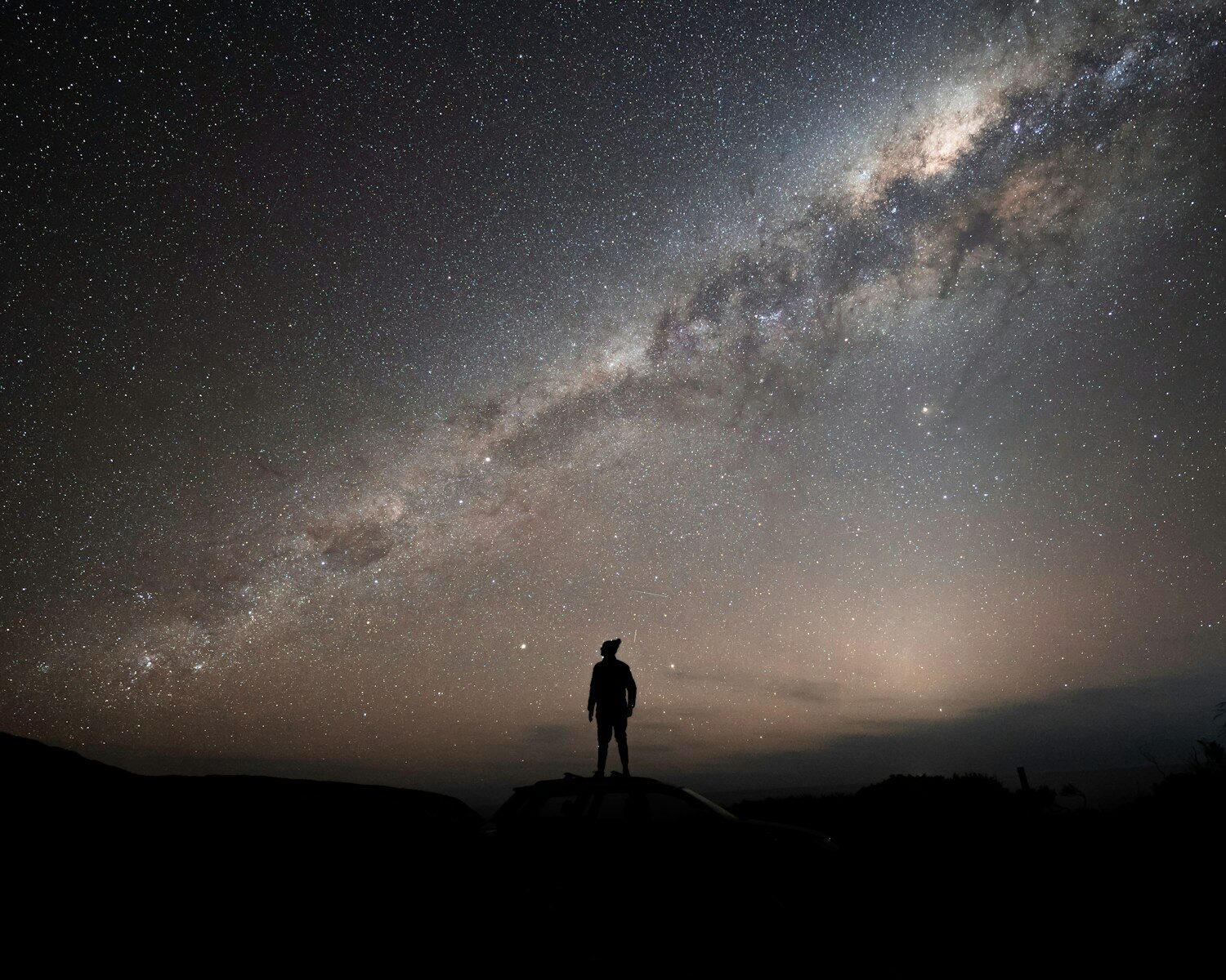 1 a man standing on top of a hill under a night sky
